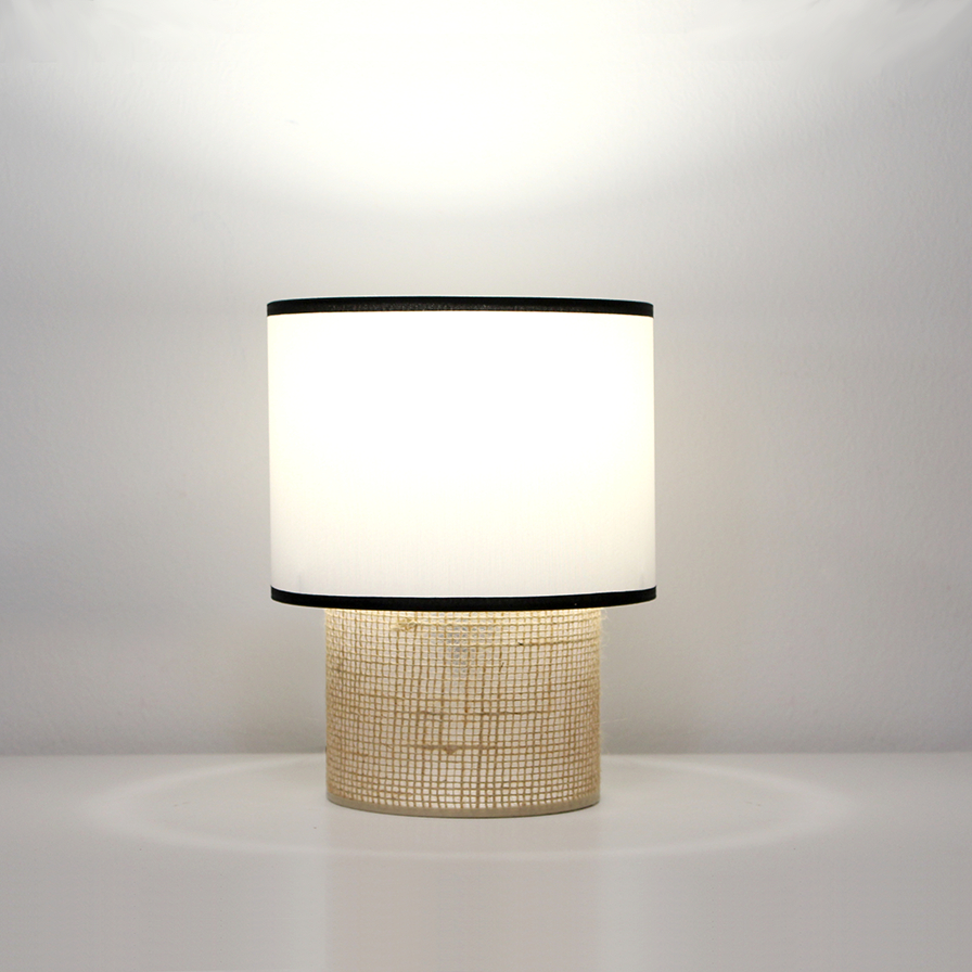 Lampe TABATA allumée diffusant une lumière douce à travers son abat-jour en coton blanc