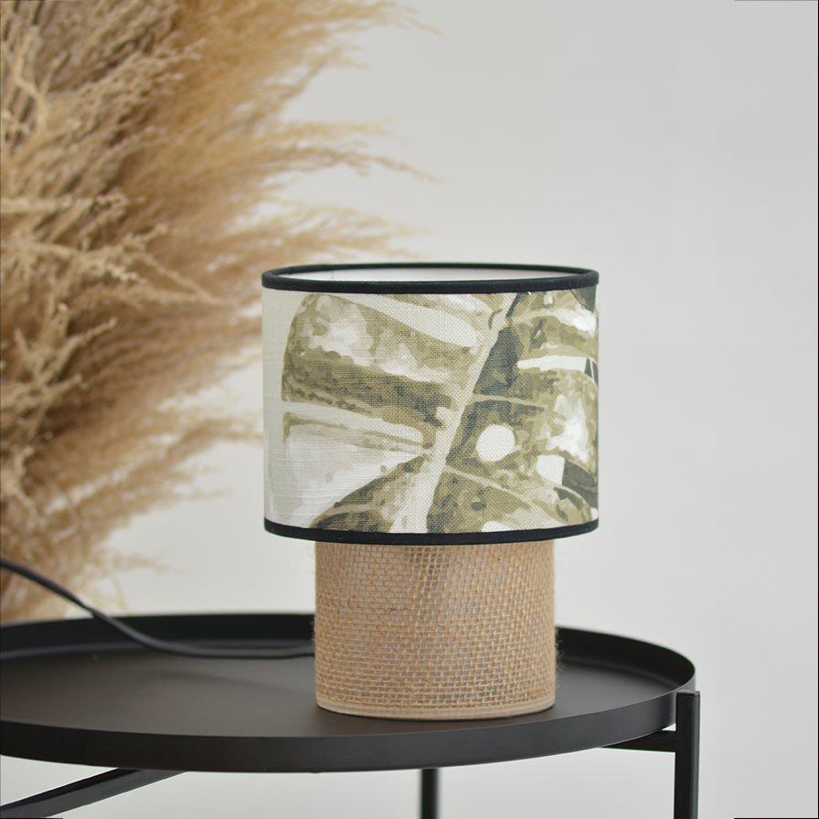 Lampe à poser TABATA jungle tropicale mise en scène sur une console noire dans un décor végétal