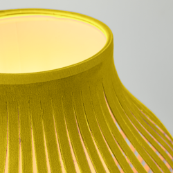 Zoom sur la lampe allumée en velours jaune design minimaliste et moderne.