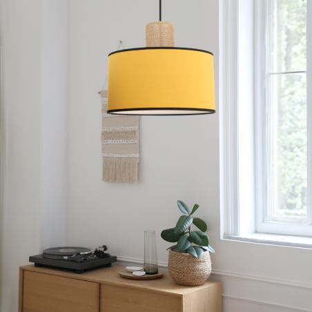 Suspension en coton jaune moutarde et sisal naturel positionner dans un intérieur blanc épurée au dessus d'une commode en bois.