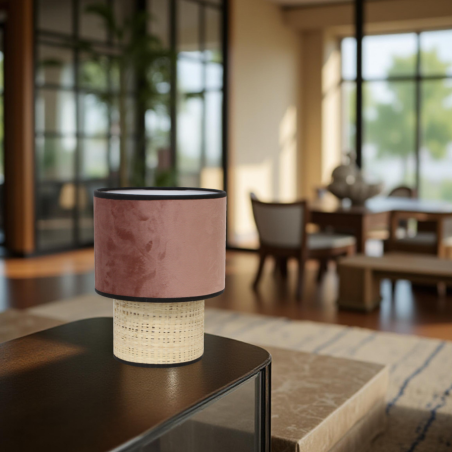 Sinaya luminaires lampe en velours rose et rotin naturel poser sur une table dans un salon chic moderne.